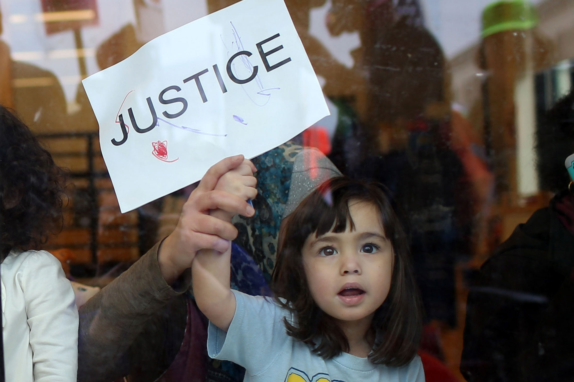 child holding a sign that says 'justice'