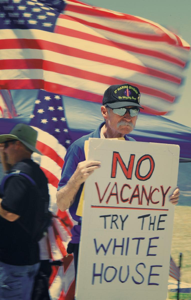 Man holding a sign that says No Vacancy-Try the White House