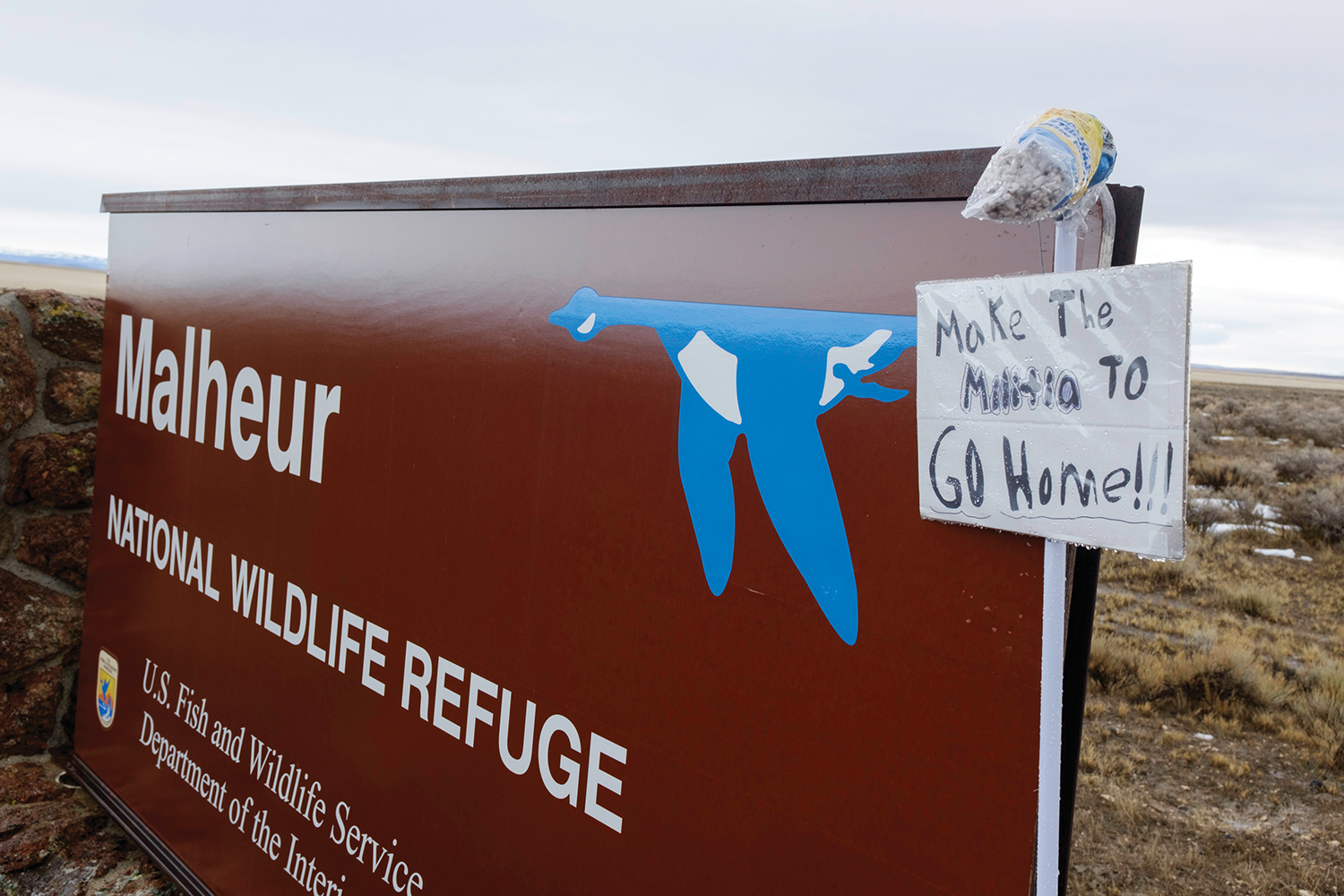 Malheur National Wildlife Refuge sign that has been covered with another sign that says "Make the Militia Go Home"