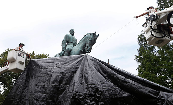 Workers drape statue of Confederate General Robert E. Lee with a tarp