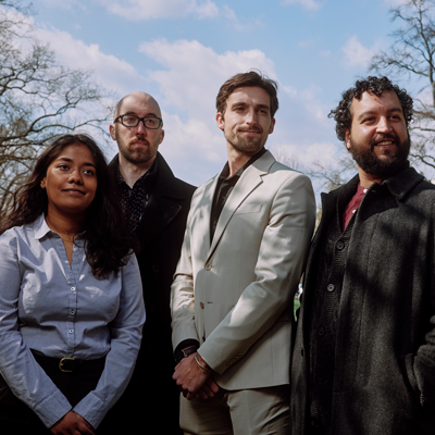 Four people stand side by side outside.
