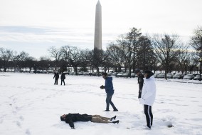 students make snow angel in front of Washington Monument