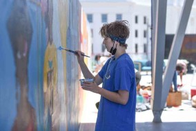 Student artist works on mural wall