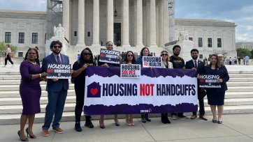 A group of activists hold a sign that says "Housing not Handcuffs"