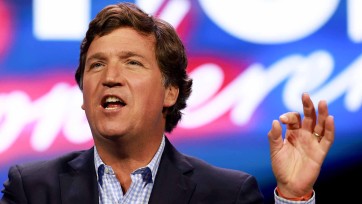 Tucker Carlson with vibrant colors displayed on video screen in background