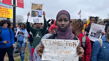 a student holds a sign that says 'time for change'