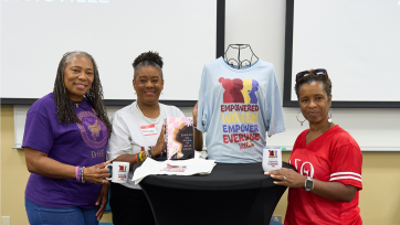 three people display branded notebooks, t-shirts, and coffee mugs