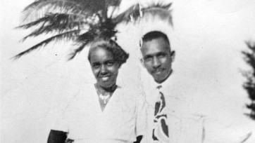 Black and white image featuring a man and woman with a palm tree in background.