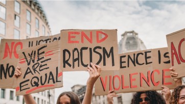 People hold up cardboard signs calling for end to racism, violence