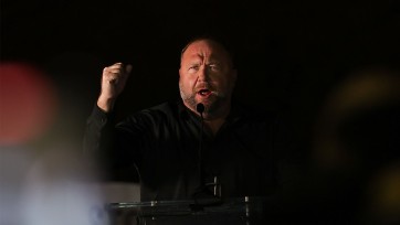 Alex Jones uses his hand to make a point at microphone