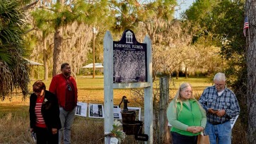 People stand by historical marker