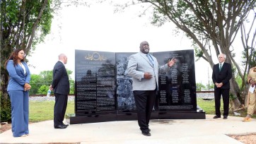 People in front of memorial made of three black granite slabs carved with the names of victims of Colfax, Louisiana, Massacre