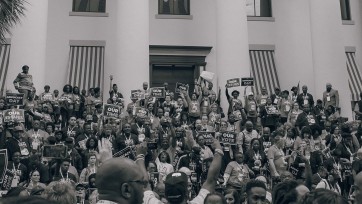 Large crowd rallies holding signs supporting voting rights