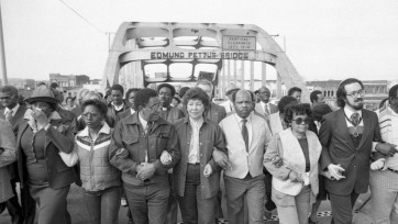 People linked arm in arm march across the Edmund Pettus Bridge in Selma, Alabama