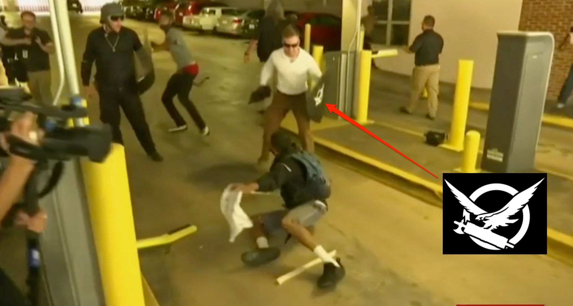 A man carrying a shield with the logo of Vanguard America on it during the attack. The white polo shirt is also part of Vanguard America's uniform.  