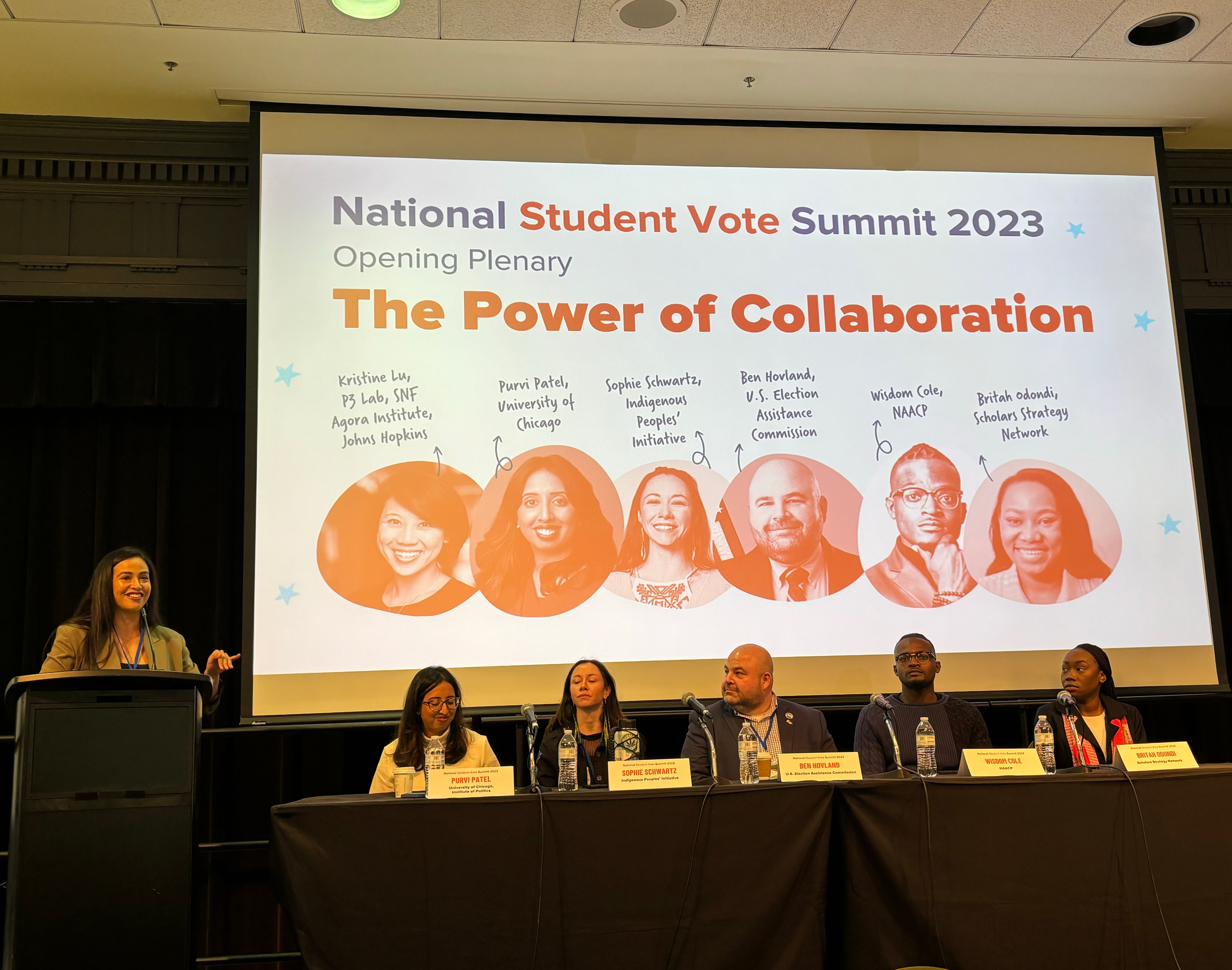 Students sit on a panel in front of a PowerPoint presentation. The slide reads "The Power of Collaboration."
