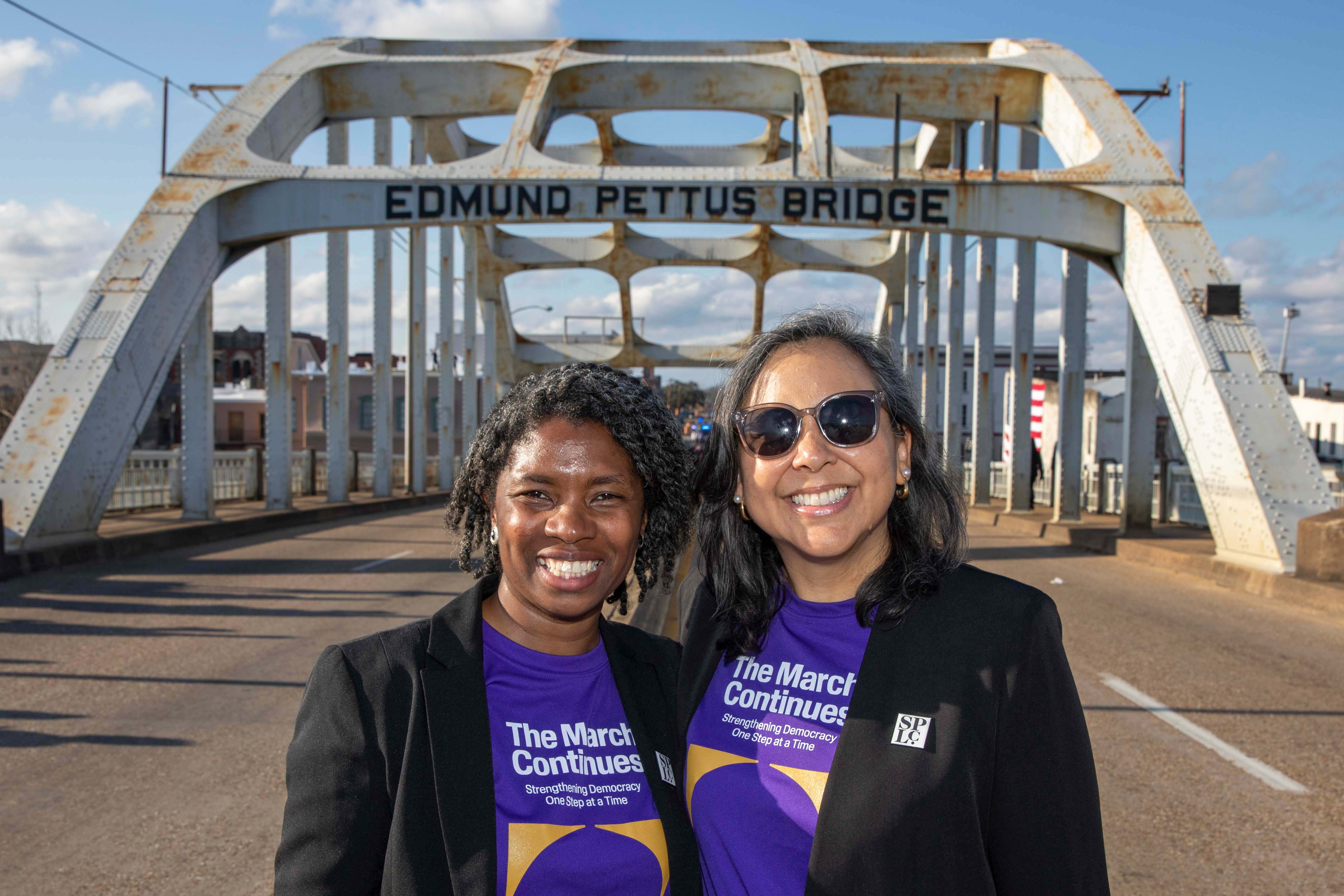Two people side by side under bridge arch.