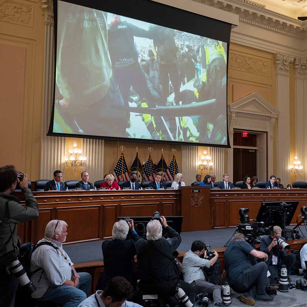 Video plays on screen above congressional panel meeting
