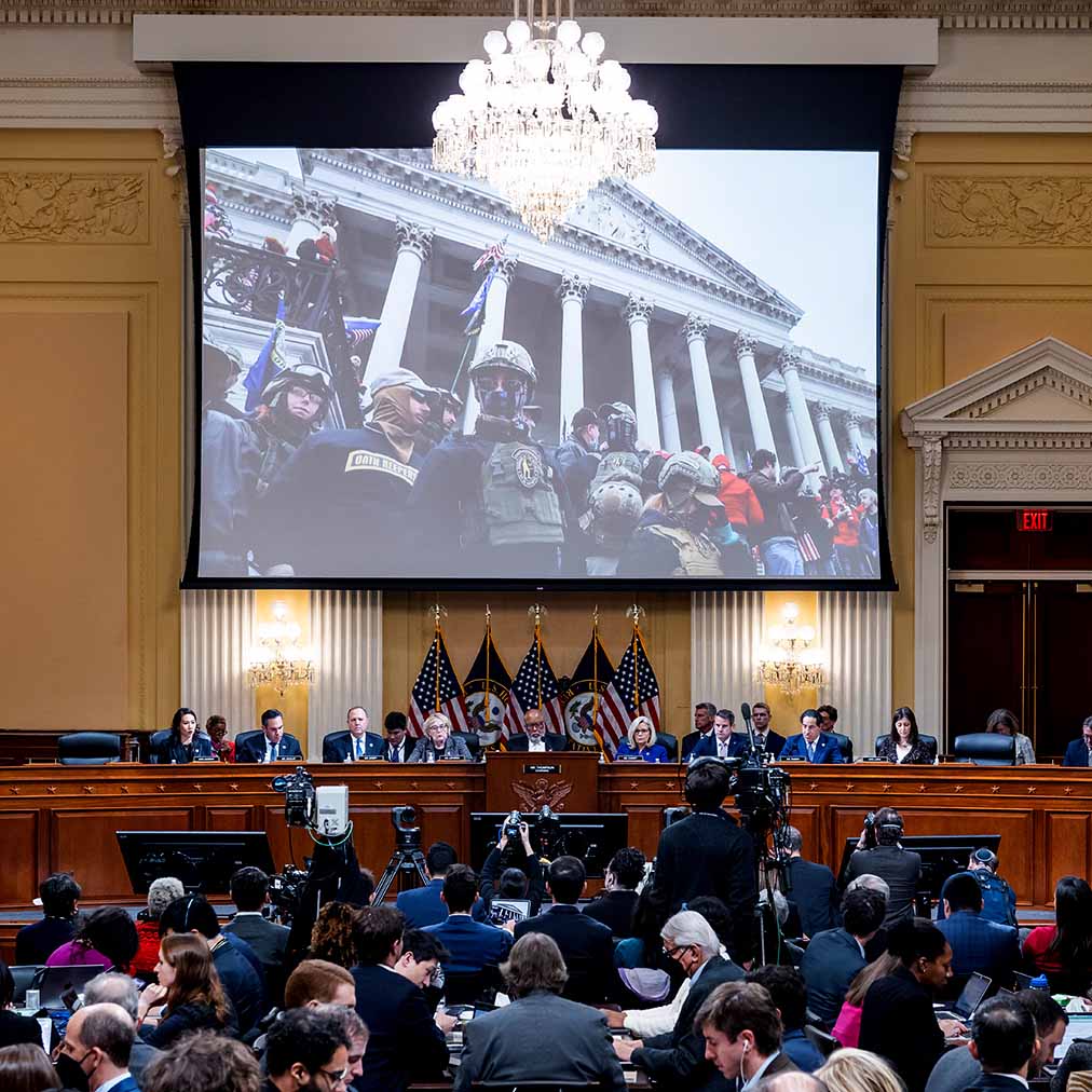 Video plays on screen above congressional panel meeting
