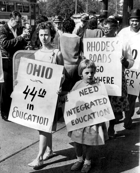 Mother and daughter walk among protesters holding signs