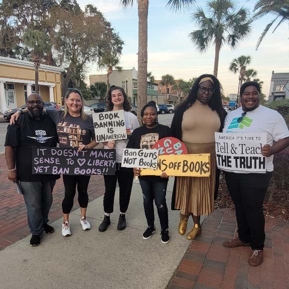 People hold signs calling for end to book bans