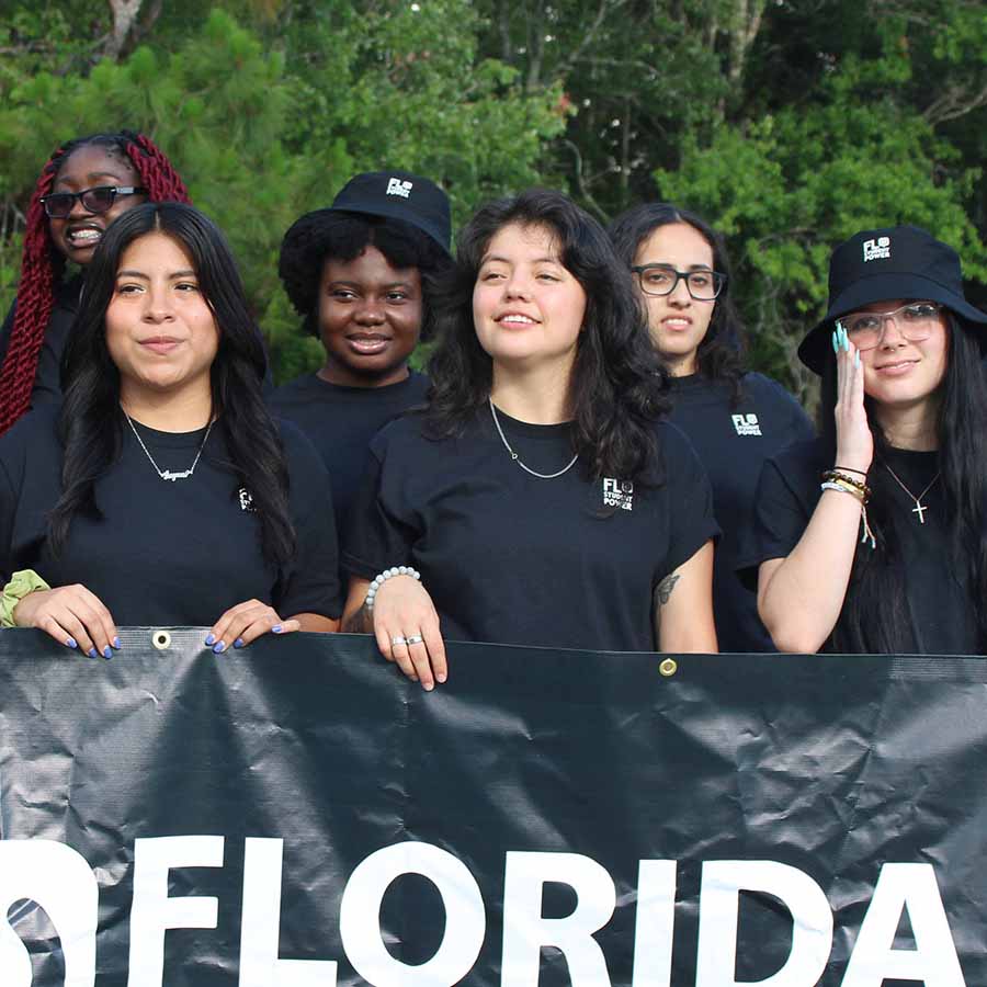 A group of young people proudly holding a banner for Florida Student Power while wearing black shirts.