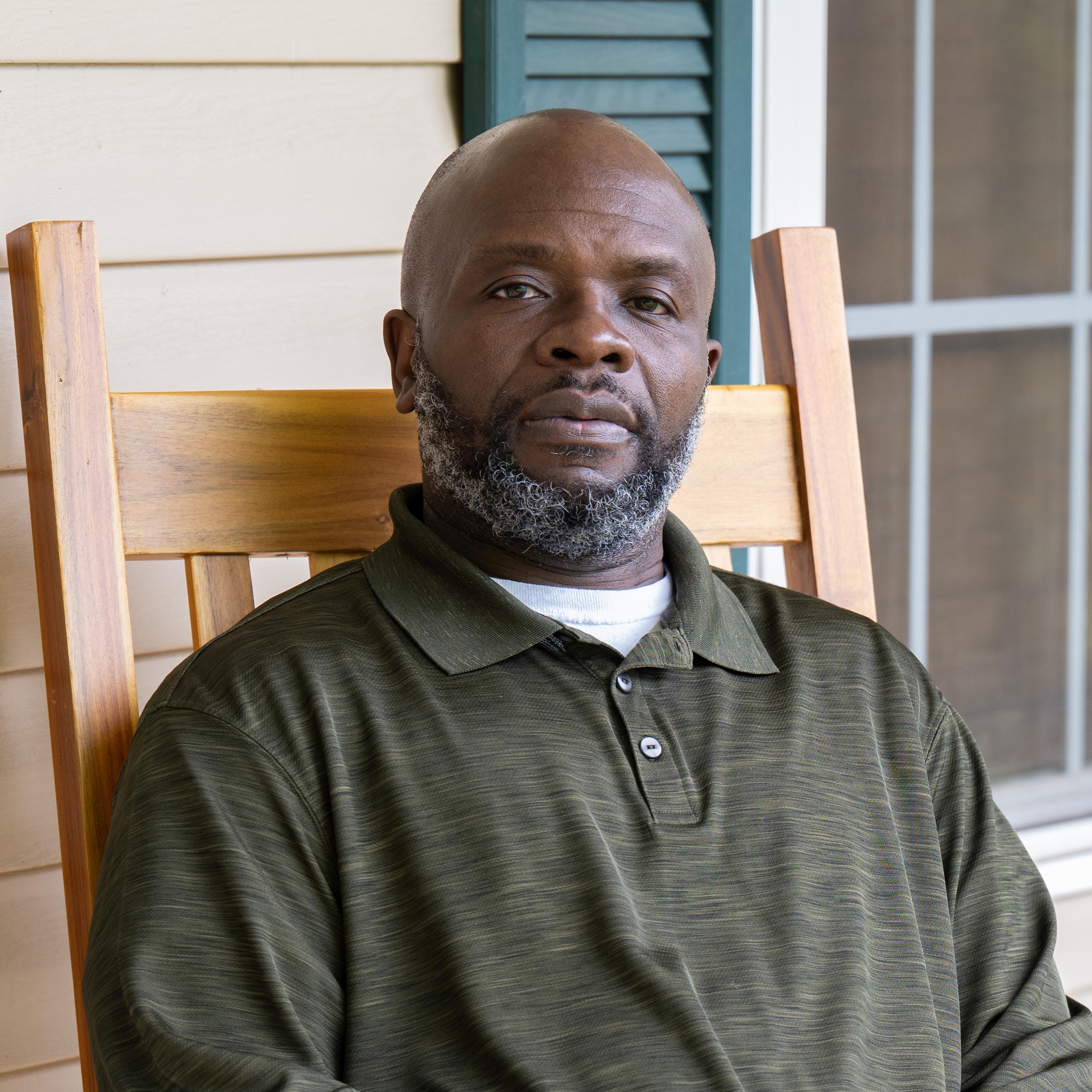 Up close portrait of adult man seated on rocking chair.