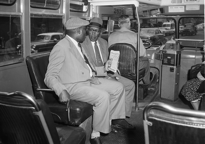 Two people sit behind bus driver in 1956