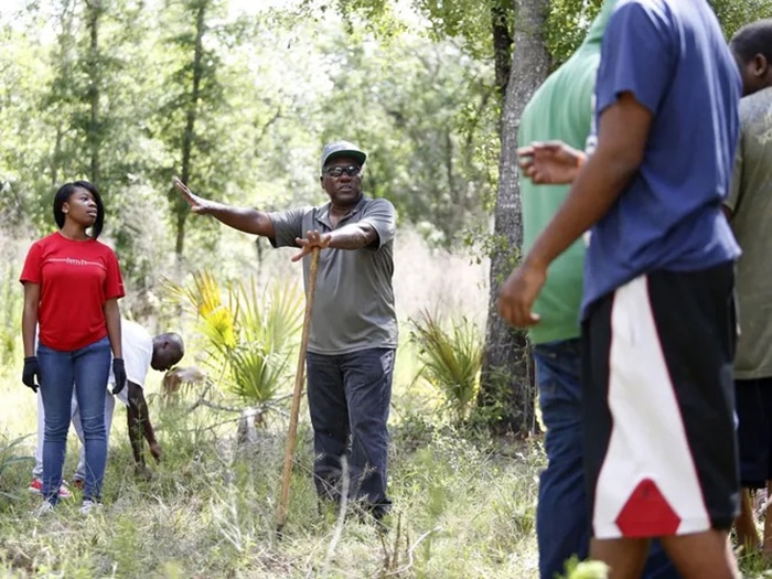 Person gestures to others in field