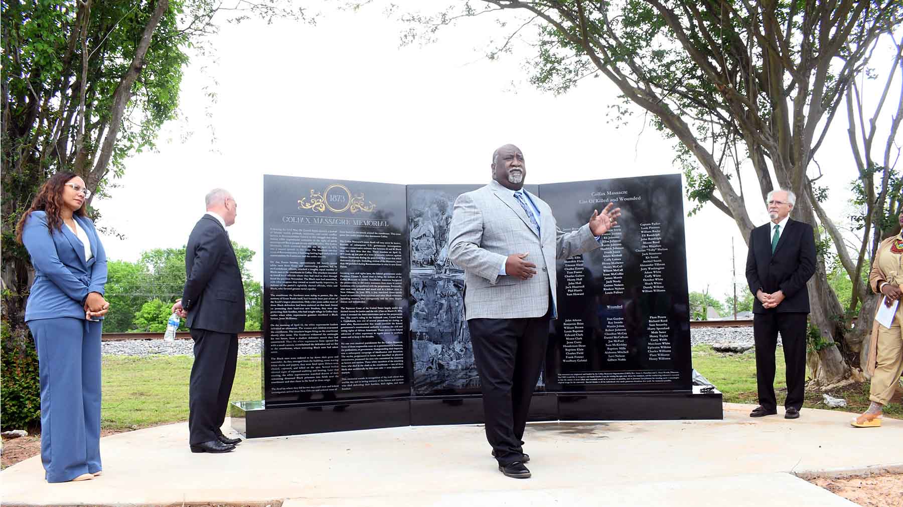 People in front of memorial made of three black granite slabs carved with the names of victims of Colfax, Louisiana, Massacre