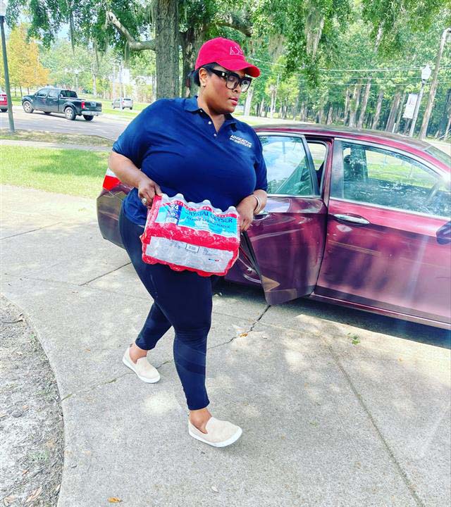 Person carries case of water bottles