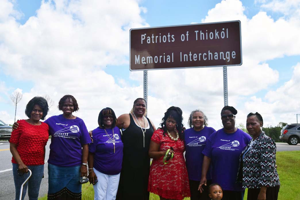 Women gather around Patriots of Thiokol Memorial Interchange road sign