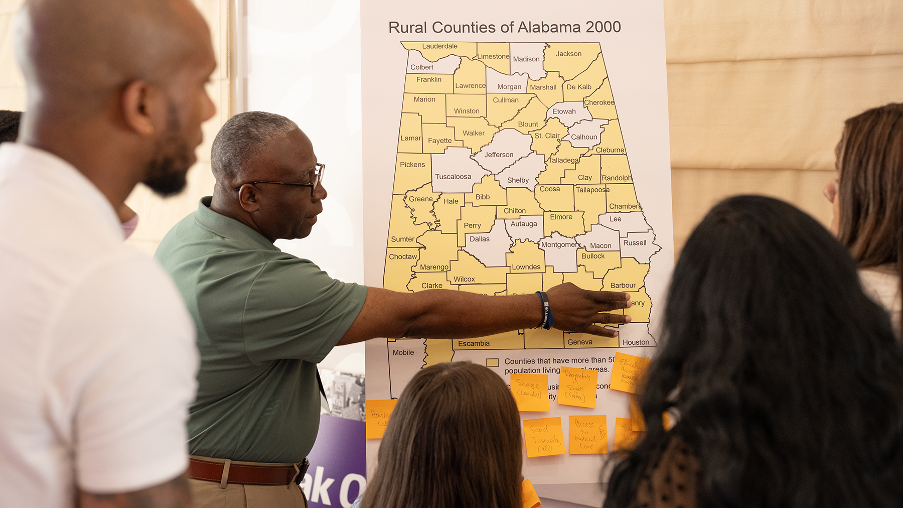 a teacher is pointing to a map of Alabama in front of a classroom