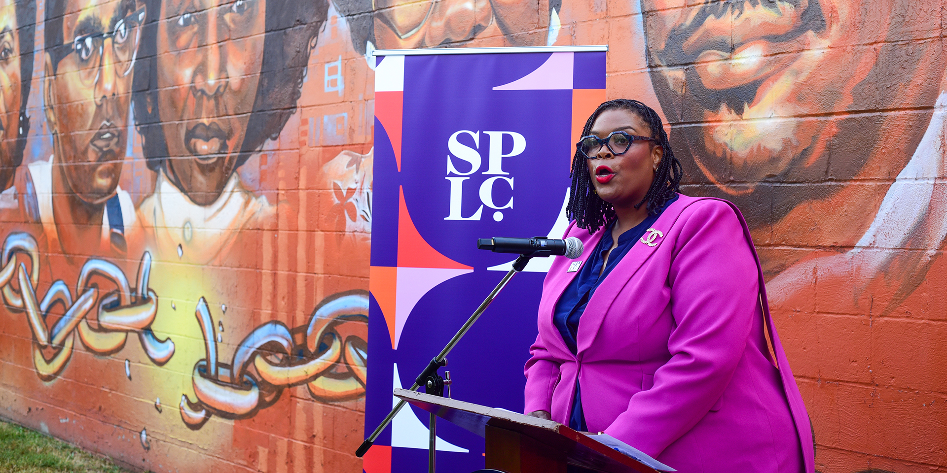 a woman stands at a podium in front of a sign that says "SPLC"