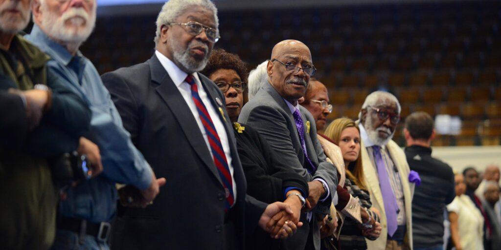 Donors hold hands at a solemn SPLC event.