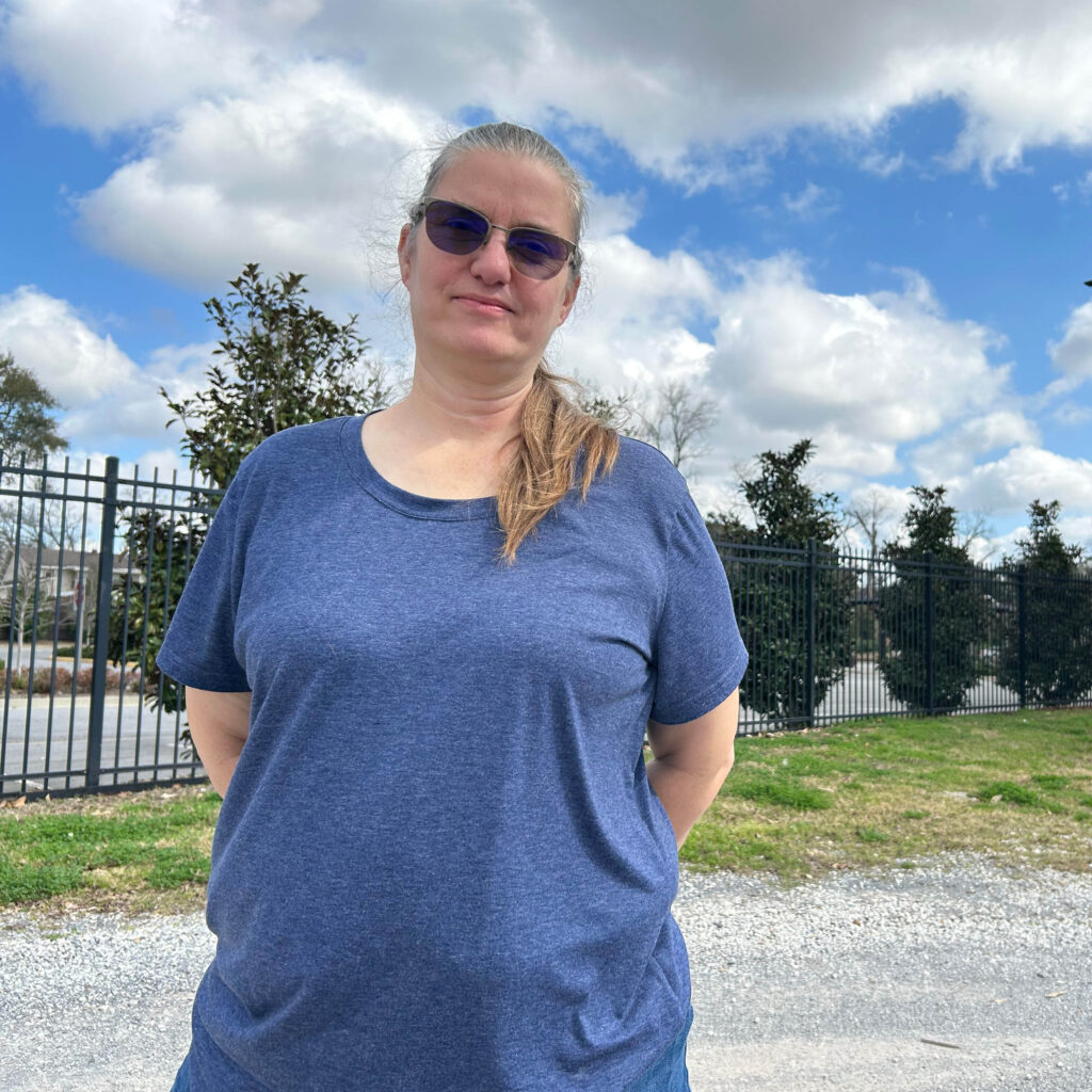 Portrait of person outside with a line of trees in background.