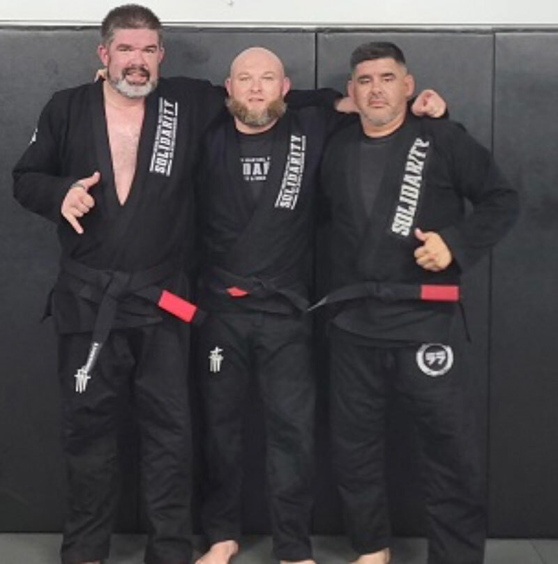 three men in black Jiu-jitsu uniforms