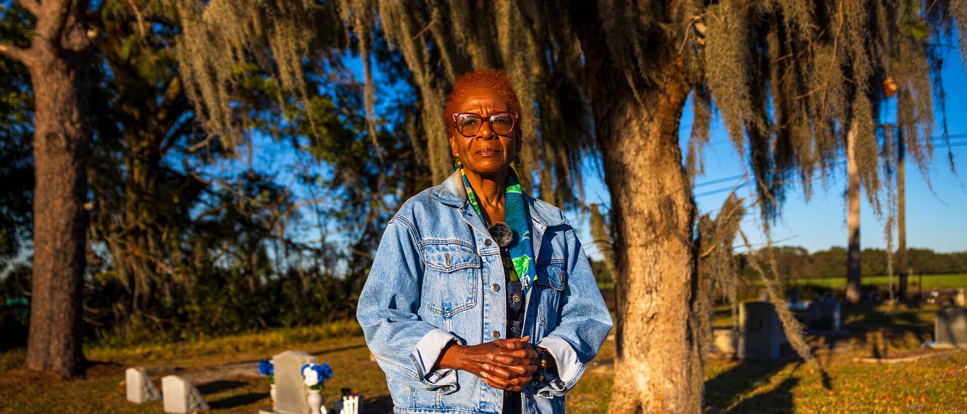 Person outside with cemetery and trees in background.