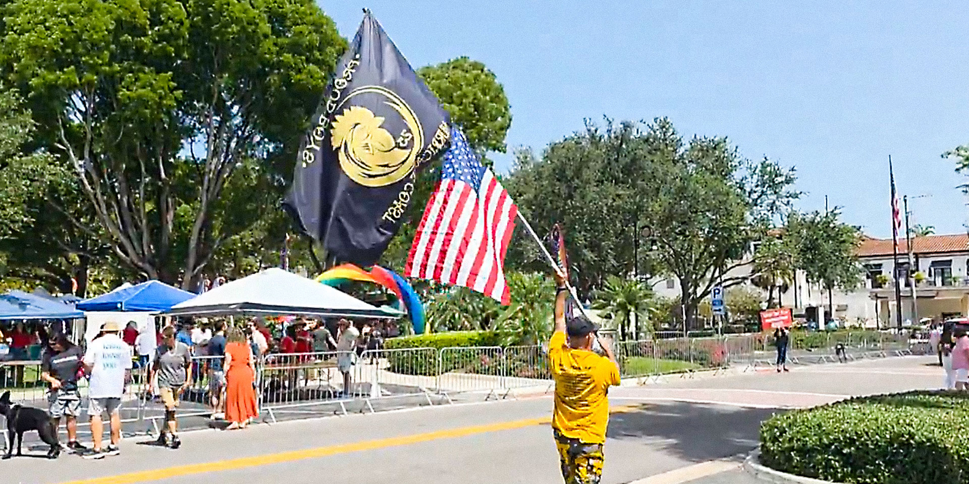 Person walks street with flags on pole.