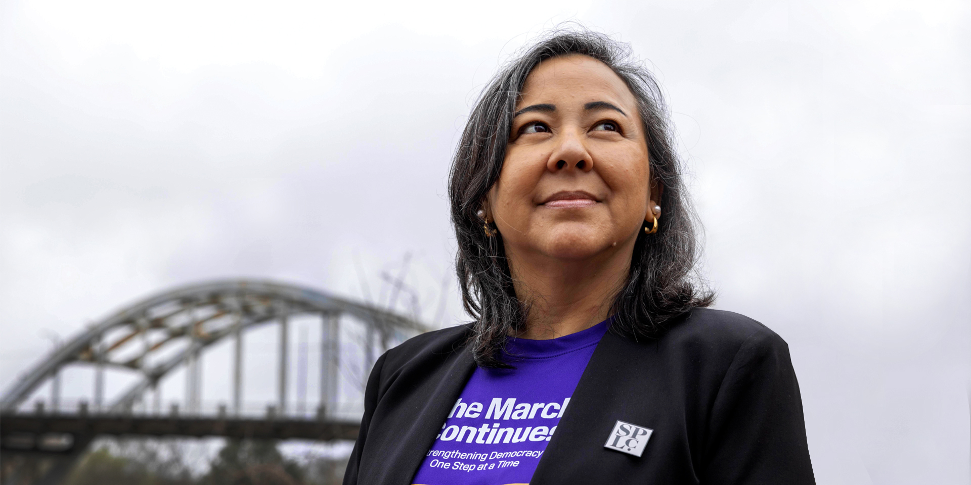 Person looking into distance with bridge in background.