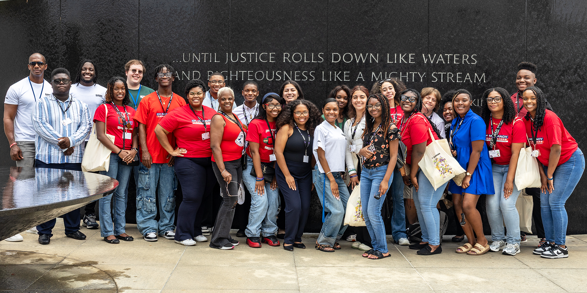 A group photo in front of an engraved quotation by Martin Luther King, Jr. that read: "...until justice rolls down like waters and righteousness like a mighty stream."