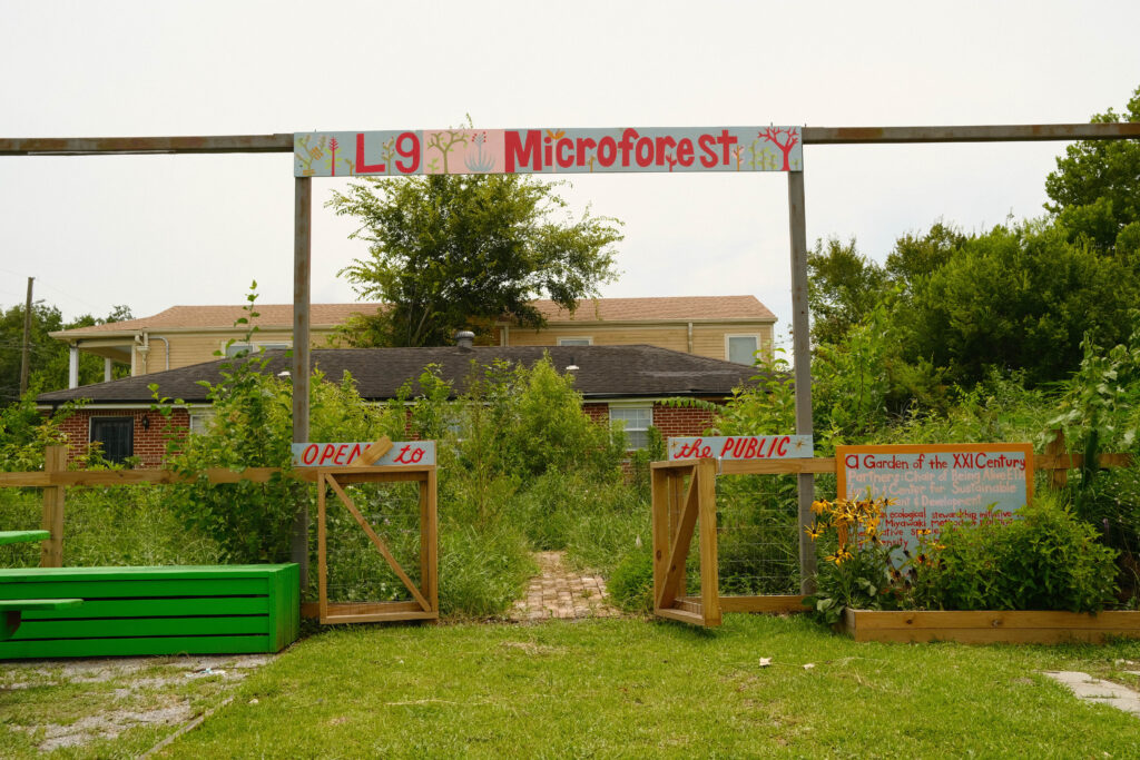 A wooden gate leads to a public garden called 'L9 Microforest.'