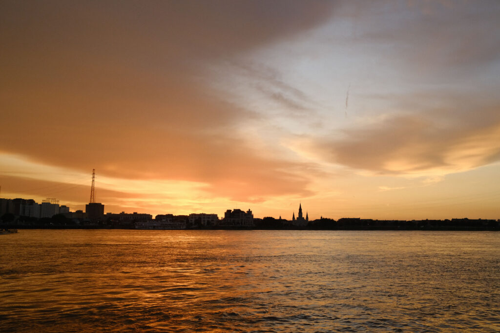 Sunset over a body of water with a distant cityscape.
