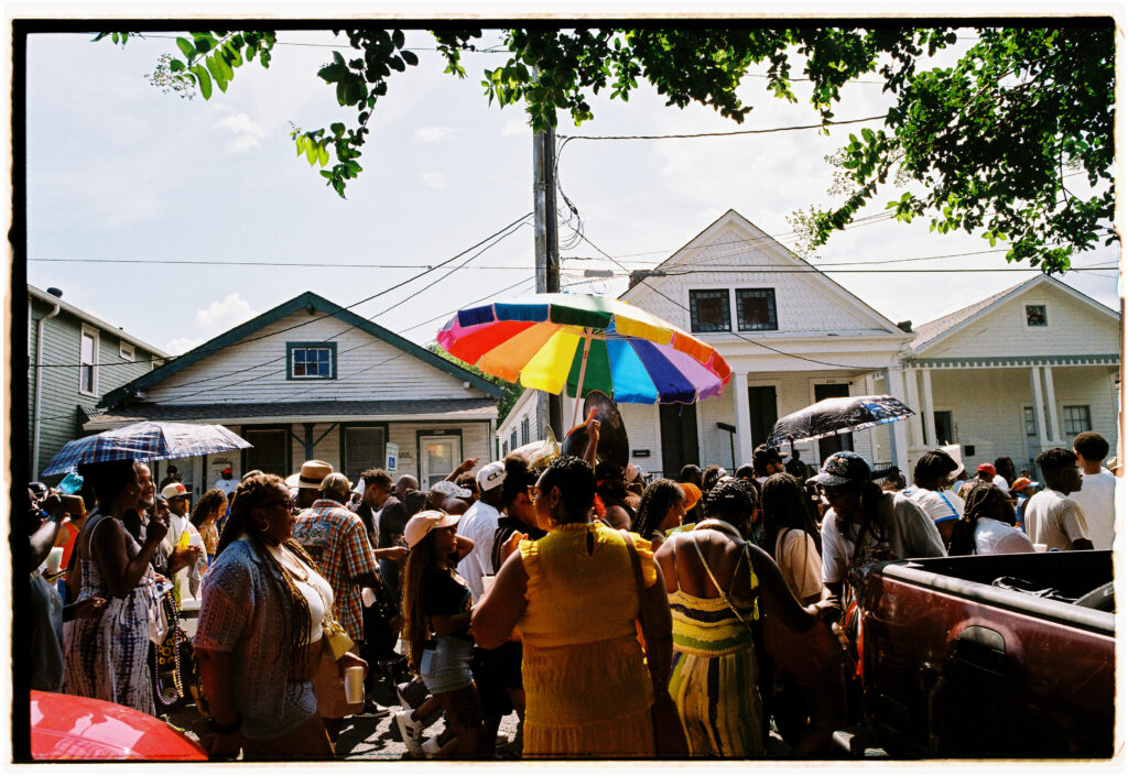A rainbow umbrella is held over a crowd of people.