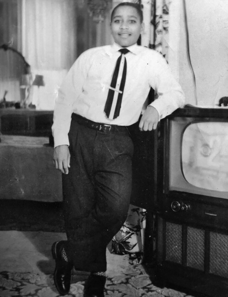 Black and white image of person leaning against a floor-box TV set.