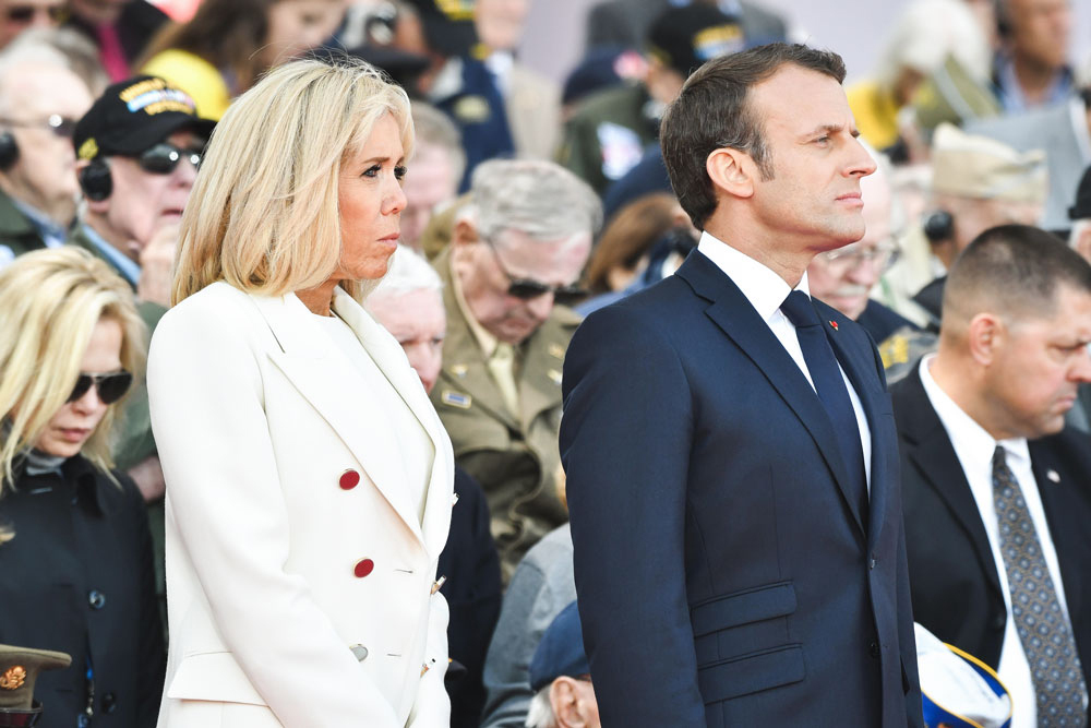 Two people stand in attention looking into distance before a crowd.