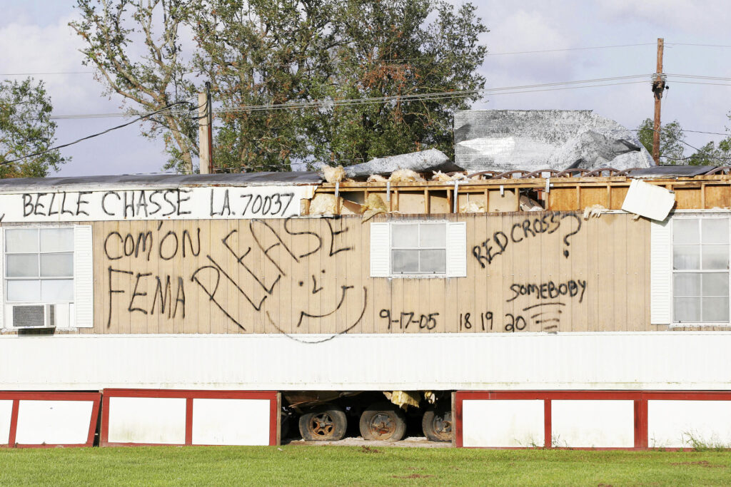 A trailer home has spray paint with request to the Federal Emergency Management Agency.