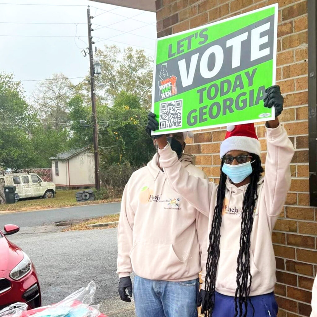 Two people in exterior setting with get-out-the-vote sign.
