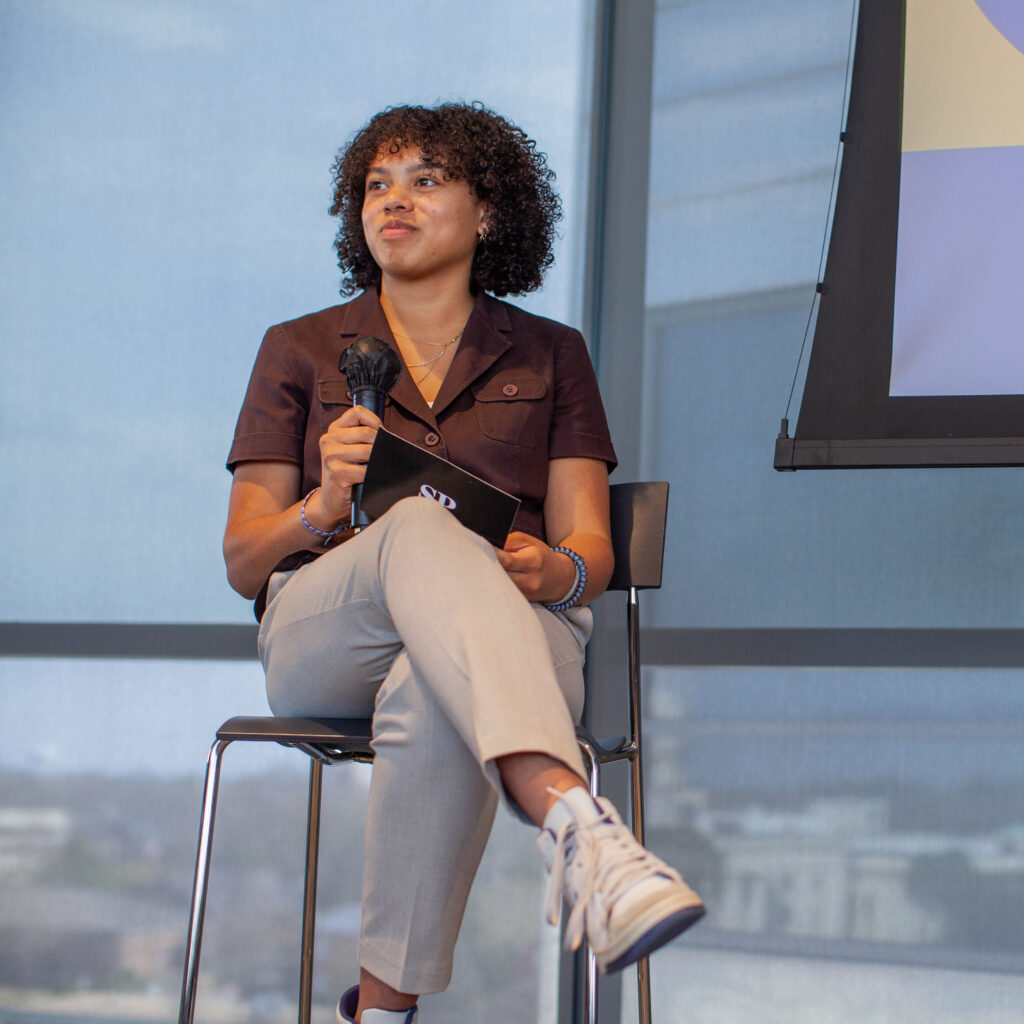 Person seated holding microphone.