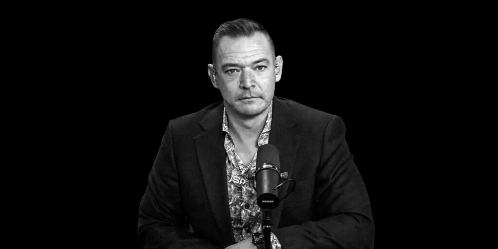 Portrait of person in front of microphone over a dark background.